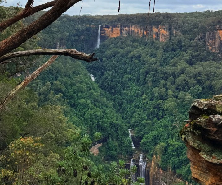 A waterfall dropping from the clifftop into a densely forested valley