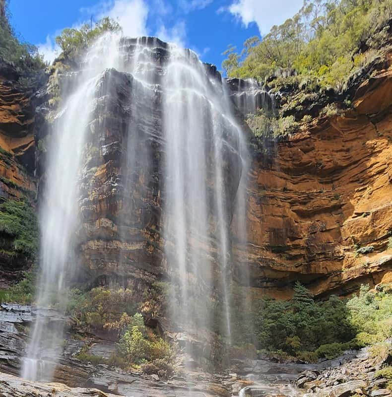 A waterfall pouring over a sandstone ledge into the gully below
